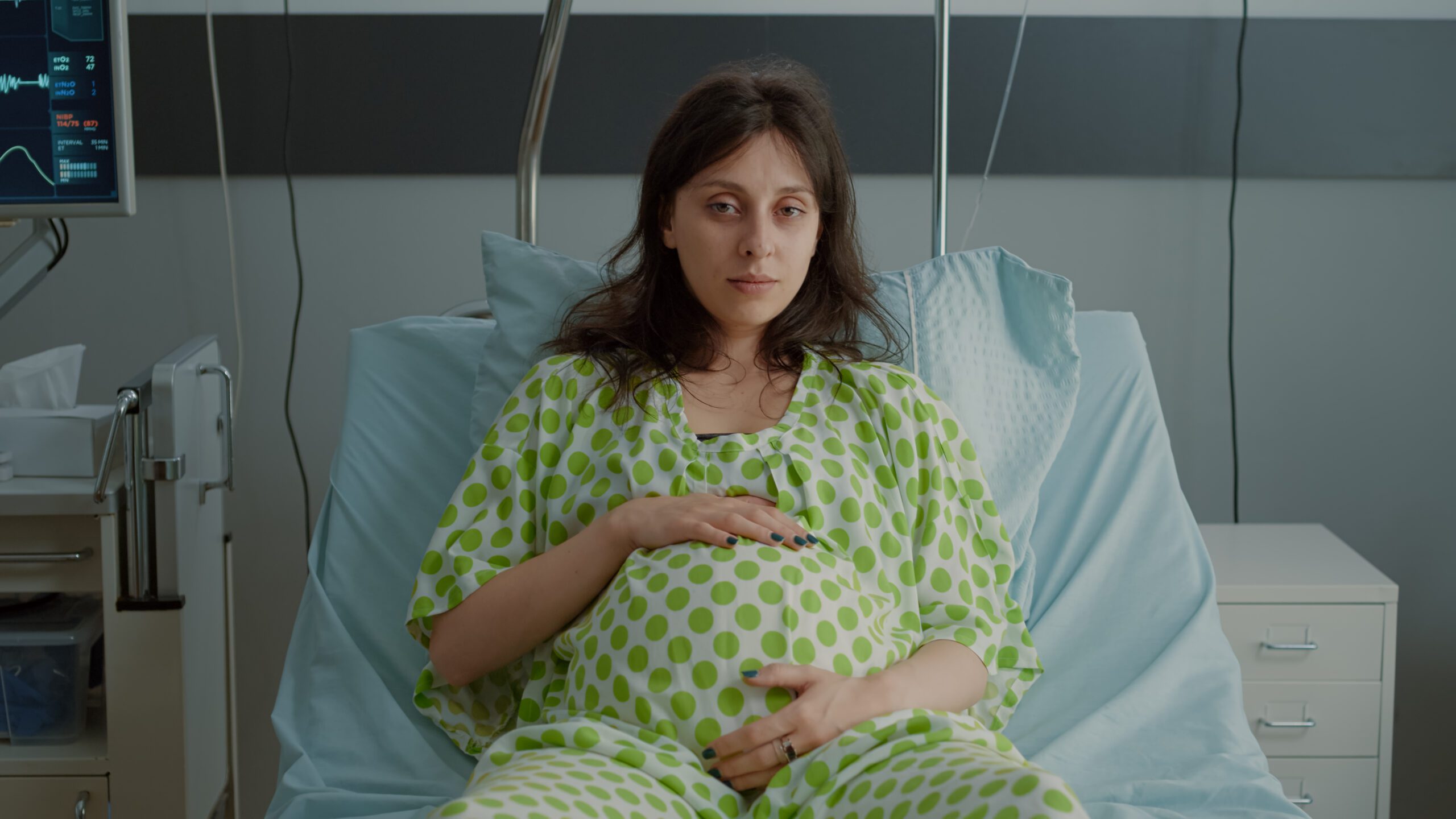 Portrait of pregnant woman laying in hospital ward bed